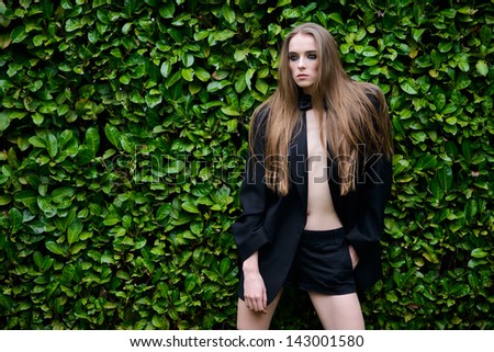 Portrait of beautiful fashion woman near wall of green leaves.