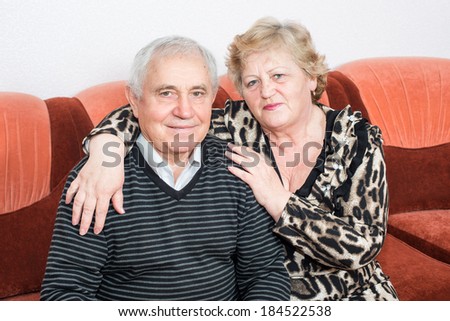 Happy senior couple sitting close together on a sofa in the house