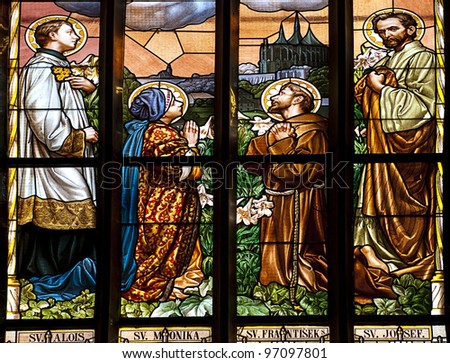 stained glass window in old church with four saints person praying
