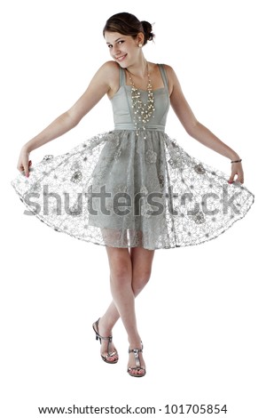 Beautiful young teenage girl with long brown hair hold skirt out and dances in lacy silver party dress. Vertical, isolated on white with copy space.