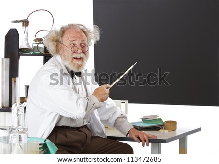 Cheerful eccentric senior scientist in his lab points to blackboard and explains his ideas. High key, horizontal, copy space.
