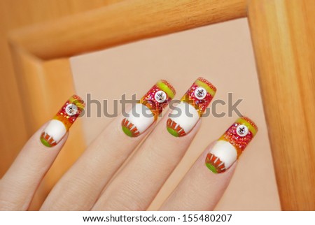 Nail design is completely made using colored acrylics on orange wooden background