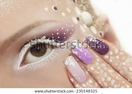Snow makeup and manicure with glitter and rhinestones in white and purple color.