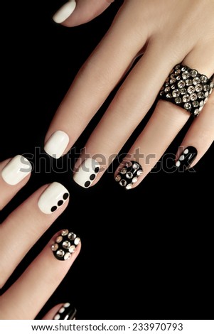 Black and white manicure with rhinestones and points at the woman\'s hand.