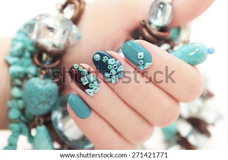 Manicure with beads and turquoise in the form of small stones and jewelry made of turquoise on the woman\'s hand.