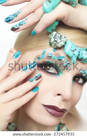Manicure and makeup with beads and turquoise in the form of small stones and jewelry made of turquoise on the woman\'s hand.