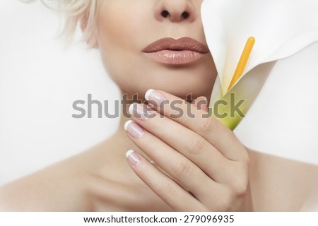 French manicure for the girl with the flower in her hand on a light gray background.