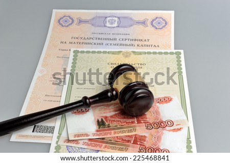 Hammer of judge with money, maternal and birth certificates on gray background