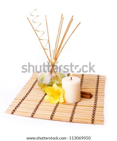 spa setting with aroma sticks, candle, yellow flower and cinnamon on bamboo mat isolated on white