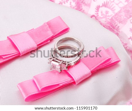 wedding rings on pink bow isolated on white