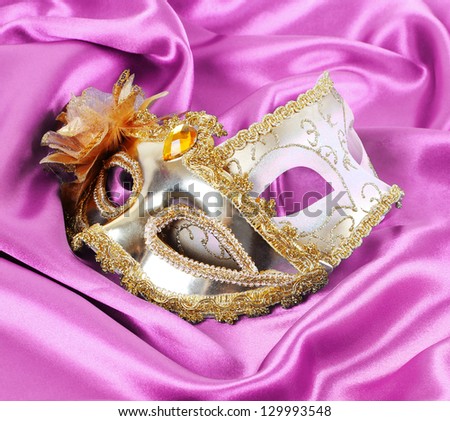 gold carnival masks on magenta silk fabric