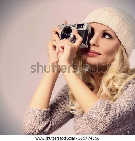 Photographer. Beautiful blonde young woman taking photo with vintage camera in studio