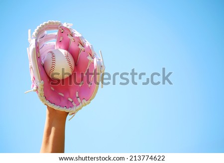 Hand of Baseball Player with Pink Glove and Ball over Blue Sky