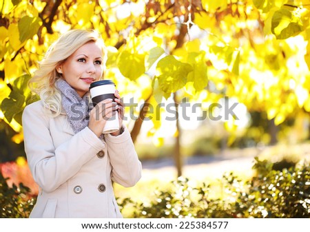 Autumn Woman with Coffee Cup. Fall. Blonde Beautiful Girl and Yellow Leaves in the Park