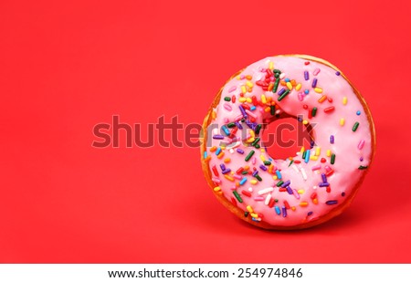 Donut with sprinkles over red background