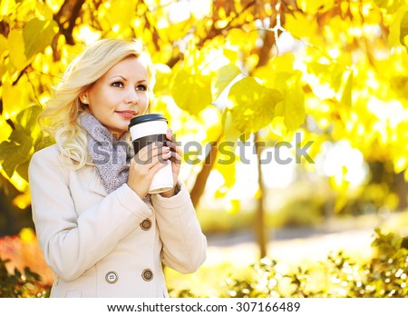 Autumn Woman with Coffee Cup. Fall. Blonde Beautiful Girl and Yellow Leaves in the Park