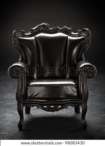old black chair, upholstered in leather, isolated on a black background scratching.
