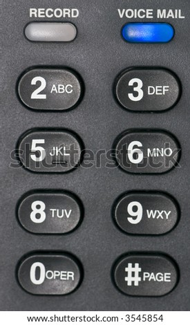 A macro shot of a desk phone\'s voice mail alert button and number buttons.