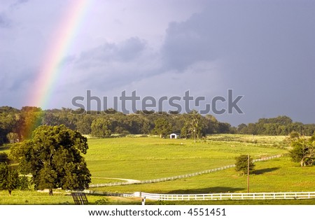 A country landscape with a rainbow accenting the sky during a break in the weather.