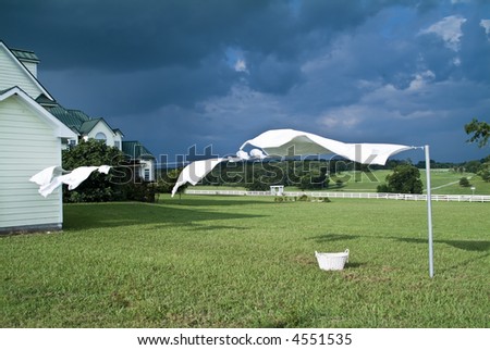 Sheets and towels on a cloths line being blown around by the wind of an approaching storm.