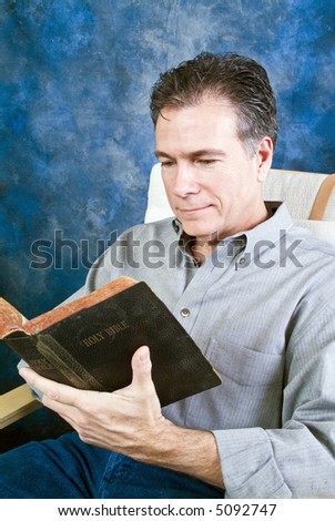 A man with a relaxed, pleasant expression on his face reading from an old bible.