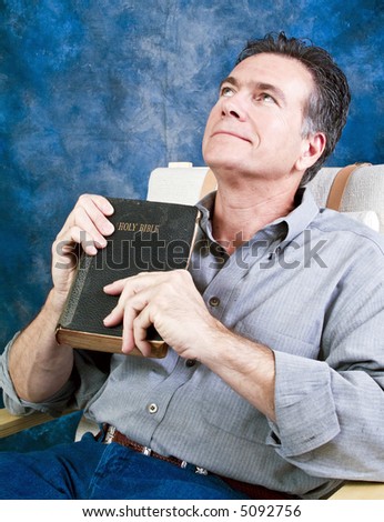 A man holding an old bible with a look of sincere gratitude on his face.
