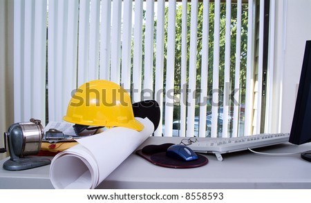 A desk cluttered with objects that indicate an engineer’s or architect’s office.