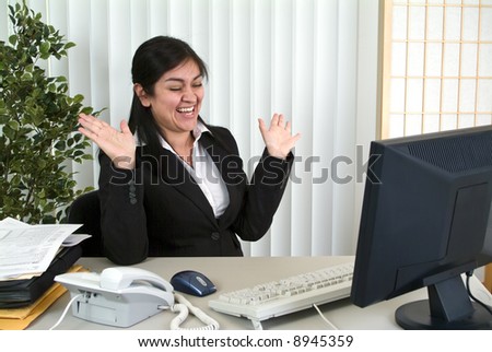 A young animated office worker laughing uproariously at something on her computer screen.