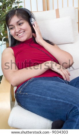 A smiling young woman with headphones over her ears, enjoying what she hears.