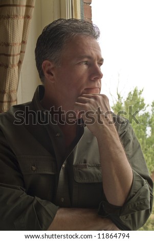 A man sitting by a window, with an anxious or worried look on his face.