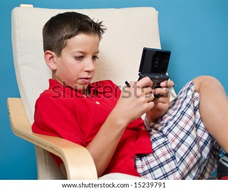 A boy concentrating on the game he is playing on his electronic game device.