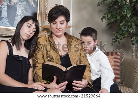 A woman teaches her two children by reading to them from the Bible.