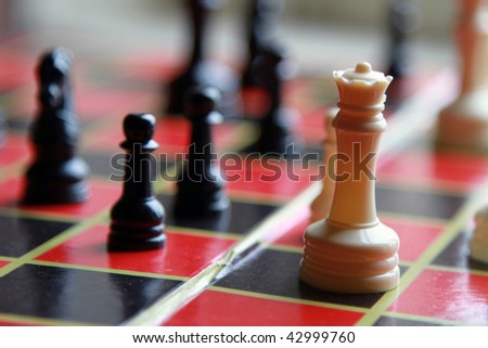A close up of a chess piece called the king sitting on a checkered chessboard.
