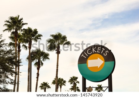 ticket sign in front of palms and blue sky