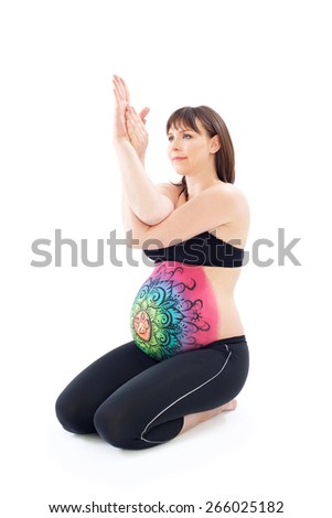 Woman with painted belly doing yoga exercise