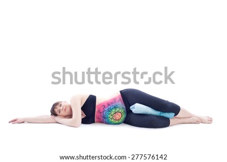 Pregnant woman with painted belly doing yoga exercise