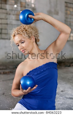 Beautiful blond woman exercises with a fitness balls in an abandoned house