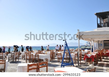 Mykonos, Greece - May 31, 2013 : Tourist are walking by dining tables of a restaurant at Mykonos waterfront, Greece