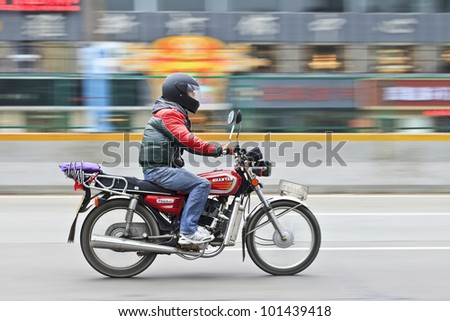 GUANGZHOU-FEB. 26, 2012. Man on a motorcycle on Feb. 26, 2012 in Guangzhou. Since Jan. 2007, the municipal government ban motorcycles in urban areas to reduce accidents and traffic problems.