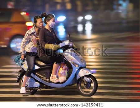 SHANGHAI-JUNE 8. Two Chinese girls on an electric bike at night time. Electric bikes are swarming on the streets in China. Nationwide, there are about 120 million of them. Shanghai, June 6, 2013.