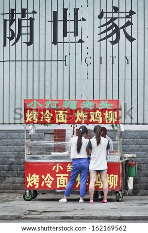 CHANGCHUN-CHINA-JULY 8. Two girls purchase street food. According to a 2007 study from the Food and Agriculture Organization, 2.5 billion people eat street food every day. Changchun, July 8, 2013.