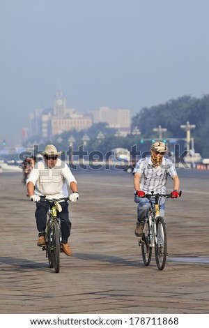 BEIJING-JUNE 1, 2013. Commuters on mountain bikes, one with smog protection. The US Embassy measures the Beijing air often as very unhealthy and even hazardous; smog protection became a must.