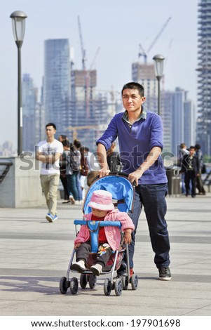 SHANGHAI-JUNE 4, 2014. Young father with baby car. After 30 years of ChinaÃ¢Â?Â?s one child policy, many families wonÃ¢Â?Â?t take advantage of allowing a second child because of rising cost of child-rearing.