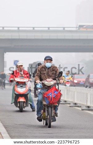 BEIJING-OCT. 11 ,2014. Old man on e-bike in smog blanketed city. A concentration of PM2.5, small particles that poses a huge health risk, hit 462 according U.S. Embassy pollution monitor in Beijing.