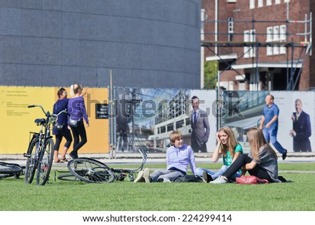 AMSTERDAM-AUGUST 24, 2014. Young people have fun chatting on Museum Square. Several museums are located around the touristy square: Rijksmuseum, Van Gogh Museum, Stedelijk Museum and Diamond Museum.
