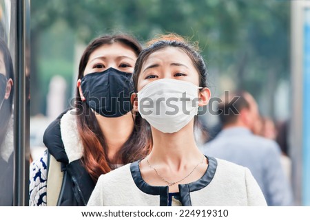 BEIJING-OCT. 19, 2014. Chinese girls with a face mask. Beijing raised its smog alert to orange because the air quality is a health threat. Face masks, once a rarity in Beijing, have now become common.