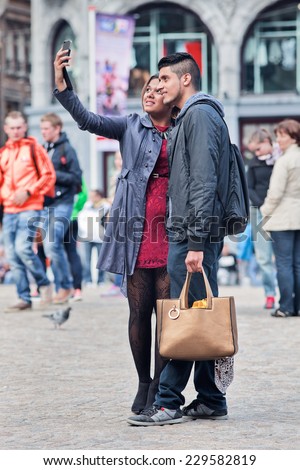 AMSTERDAM-AUGUST 26, 2014. Well dressed couple takes selfie on Dam Square. The city is a source of inspiration for fashionable people. there are many ways to soak up Amsterdam\'s fashionable vibe.