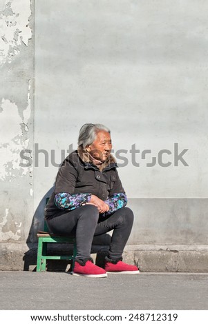 SHANGHAI-DEC. 5 2014. Old Chinese woman sit outside on a small chair. The elderly population (60 years or older) in China is 128 million or one in every ten people, which is the largest in the world.