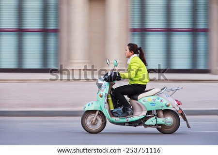 SHANGHAI-JAN. 2, 2015. Fashionable girl on e-bike. Estimated 200 million Chinese now use e-bikes,  1,000-fold increase from 15 years ago. About 90 percent of world\'s e-bikes were sold in China in 2012
