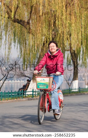 HANGZHOU-DECEMBER 23, 2009. Cheerful woman on rental bike. Currently, Hangzhou runs the largest bike-share program in the world with 250,000 trips a day with more than 60,000 bikes and 2,177 stations.